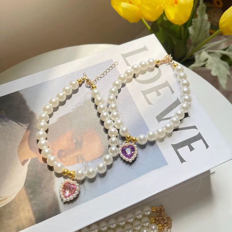 Two pearl pet necklaces with pink and purple heart pendants